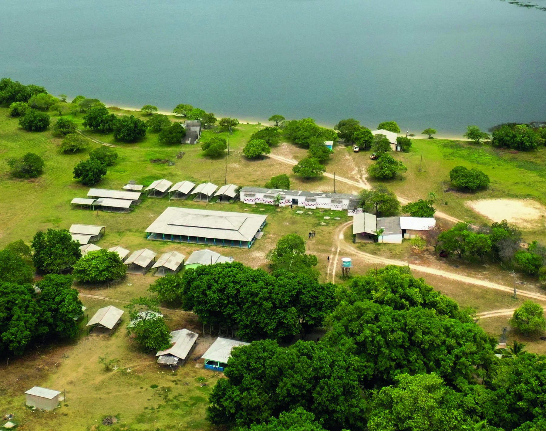 Vista aérea de uma comunidade indígena cercada pela vegetação e por um lago