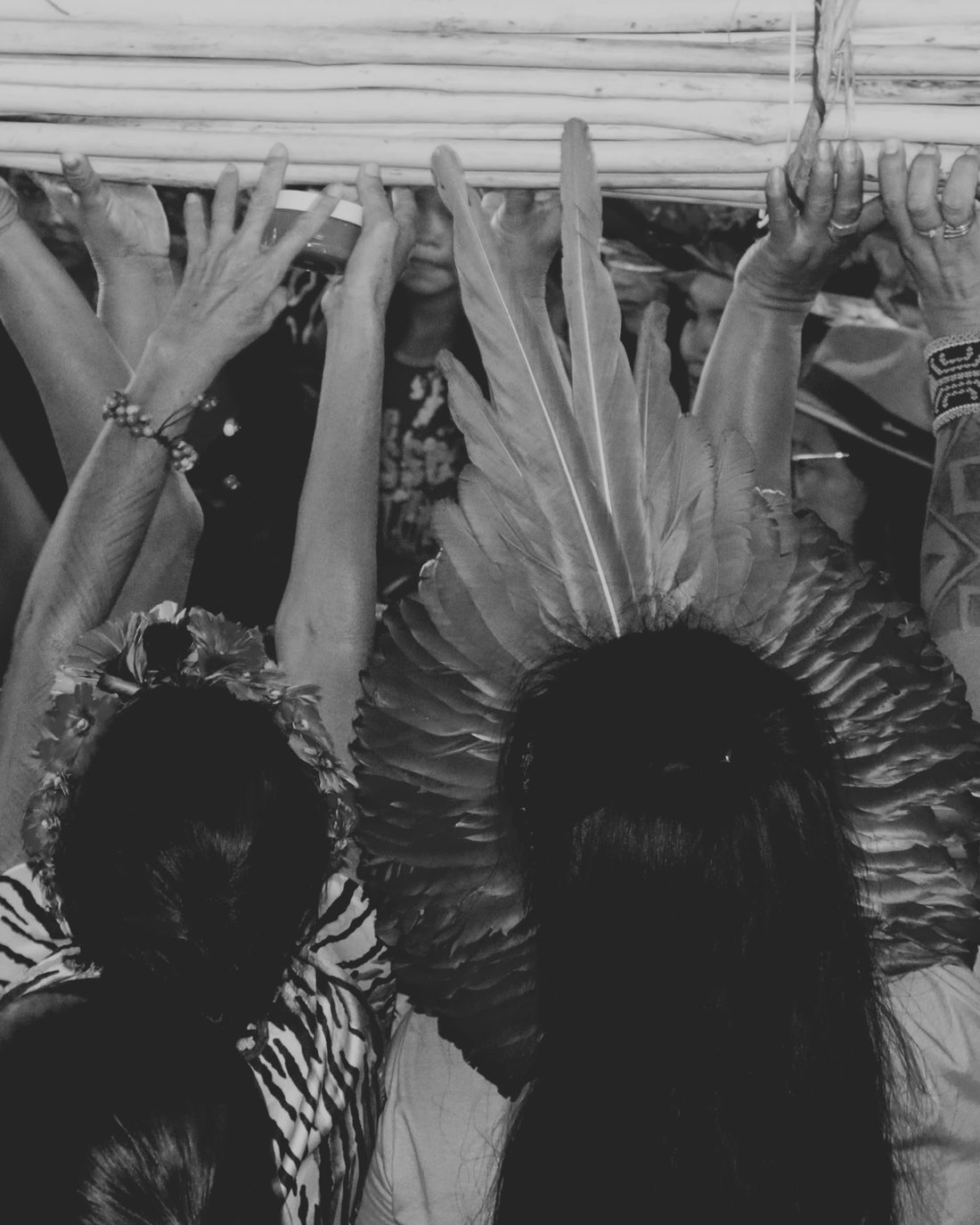 Participantes erguem as mãos durante uma assembleia indígena