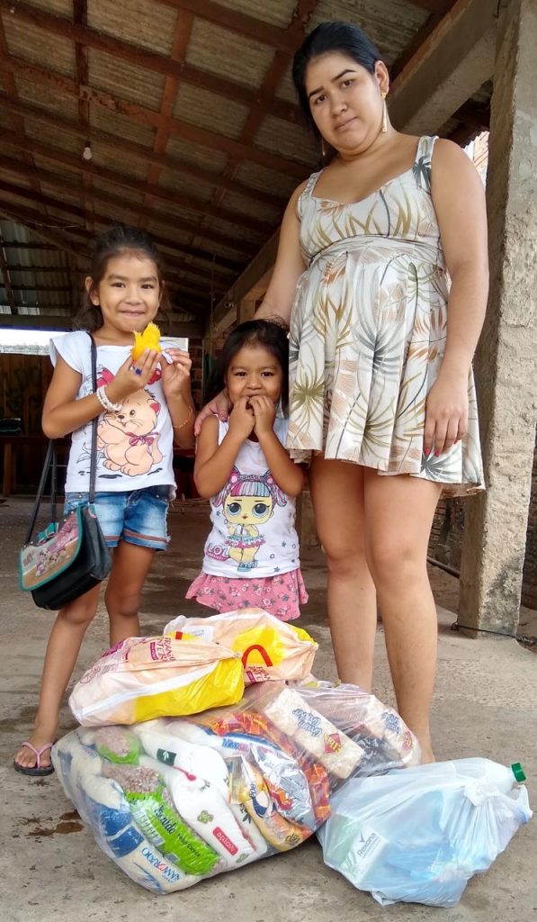 Izaura Neves Macuxi e as duas filhas ao receber os itens de alimentação e o kit de higiene