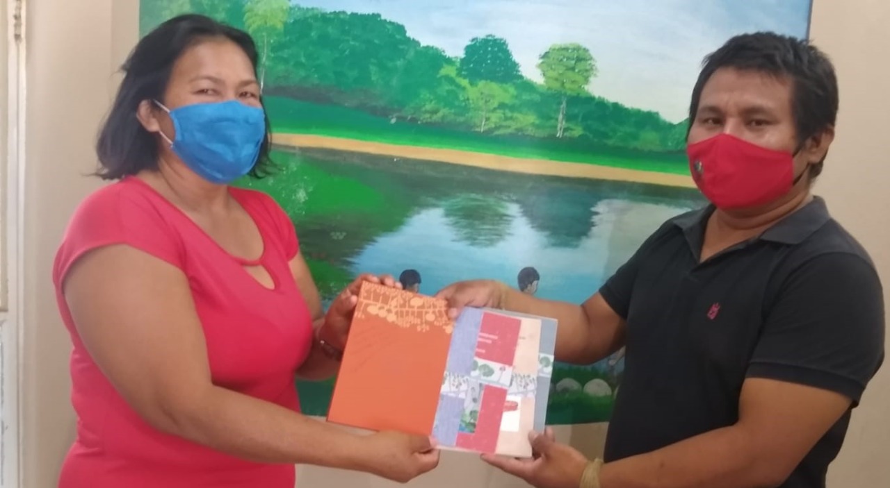 A coordenadora da medicina tradicional, Edilasomara Sampaio entrega do caderno ao coordenador Enock Taurepang.